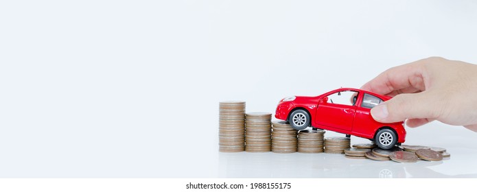 Business man and close up hand holding model of toy car red on over a lot money of stacked coins - insurance, loan and buying car finance concept. buy and installments down payment a car