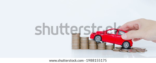 Business\
man and close up hand holding model of toy car red on over a lot\
money of stacked coins - insurance, loan and buying car finance\
concept. buy and installments down payment a\
car