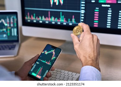 Business man crypto trader investor analyst holding smartphone and gold bitcoin coin buying cryptocurrency tokens analyzing stock market data investment risks using online trading mobile app concept.