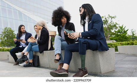 Business Man With Disability Adjusting His Prosthetic Leg While Teamwork Having Lunch Break Outside The Office