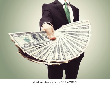 Business Man Displaying a Spread of Cash over a green vintage background