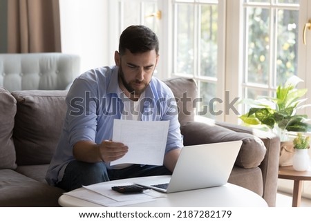 Business man doing paperwork at home, reading financial report, learn documents, examining utility bills, analyze tariffs looks focused, making payment for rent, reviewing taxes, paying for mortgage