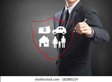 Business Man Drawing Shield Protecting Family, House, Car Money.  Insurance Concept