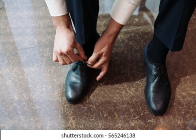 Business man dressing up with classic, elegant shoes. Groom on wedding day, tying the laces and preparing. - Shutterstock ID 565246138