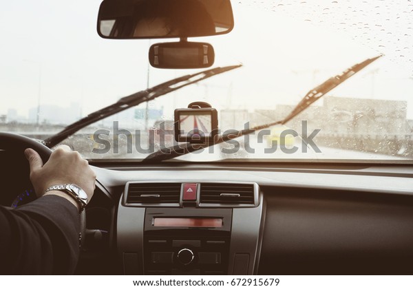 Business man is driving a car in raining day with\
moving wiper blades