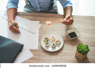 Business Man Eating Sushi At Lunch Time While Working At New Project - Senior Entrepreneur Inside Creative Studio - Smart Work And Food Delivery Concept - Focus On Hands