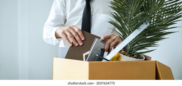 Business Man Employee Packing Notebook And Picking Up Personal Belongings Into Brown Cardboard Box To Leaving Workplace When Resignation From Work Or Changing Work