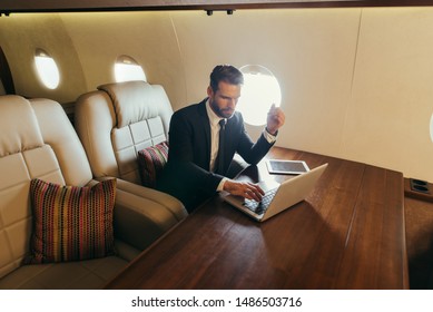 Business man flying on a private jet. Working onboard of the airplane. Successfull businessmen lifestyle. Concept about traders, affiliate marketing and sales people