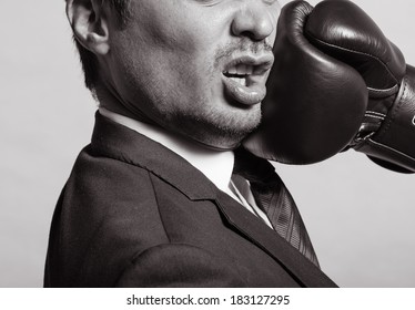 Business man getting punch with boxing glove.