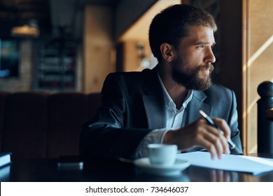business man with glasses thinks looks out the window, cafe, documents, cup of coffee                              