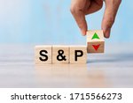 business man Hand change wood cube block with S&P text to UP and Down arrow symbol icon. Interest rate, stocks, financial, ranking, mortgage rates and Cut loss concept