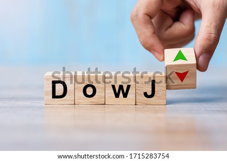 business man Hand change wood cube block with Dow J text to UP and Down arrow symbol icon. Interest rate, stocks, financial, ranking, mortgage rates and Cut loss concept
