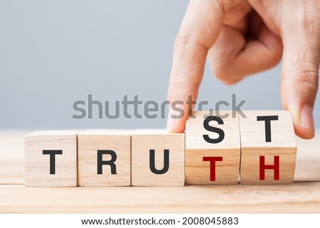 Business man hand change wooden cube block with TRUST and TRUTH business word on table background. Trustworthy, faith, beliefs and honesty concept