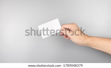 Business man hand holding credit card isolated on white background.
Plastic name card mock up show template display front design. 
Credit card instead of cash payment concept.  