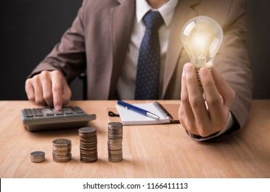 Business Man Hand Holding Lightbulb With Using Calculator To Calculate. Concept Idea Saving Finance.