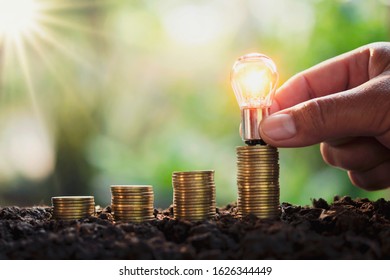 Business Man Hand Holding Lightbulb Money Stack. Idea Saving Energy And Accounting Finance Concept