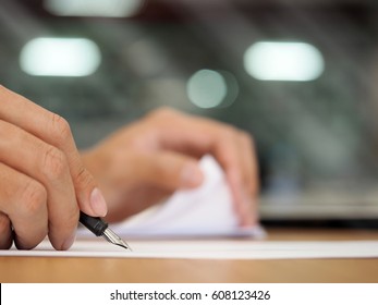 Business man hand holding pen writing on papers at seminar or signing contract making a deal