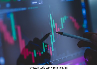 Business Man Hand Holding Pencil Points To Stock Market Graph Analysis On Monitor Screen. Economic And Financial Concept. Seletive Focus. 