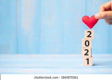 Business Man Hand Holding Red Heart Shape Over 2021 Wooden Cubes On Blue Table Background With Copy Space For Text. Business, Resolution, New Year New You And Happy Valentine’s Day Holiday Concept