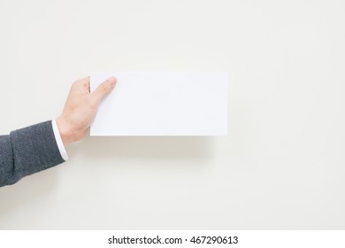 A Business Man Hand Holding White Blank Envelope On White Background With Copyspace. Empty Post Document Design Mockup, Postcard Template For Business Background Concept