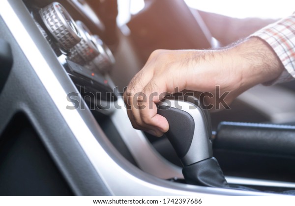 business man hand using a car automatic gear\
stick. shift transmission driving. automobile safe driver on the\
road concept