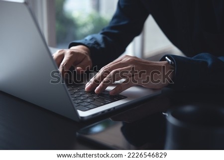 Business man hands typing on laptop computer keyboard, searching information, surfing the internet on dark office desk, distance job, online working, business and technology concept