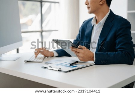 Business man hands is typing on a laptop and holding smartphone at modern ffice
