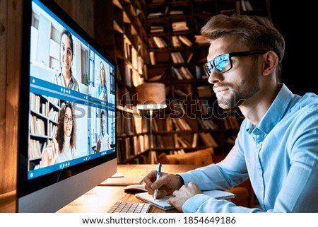 Business man having virtual team meeting on video conference call using computer. Social distance employee working from home office talking to diverse colleagues in remote videoconference online chat.