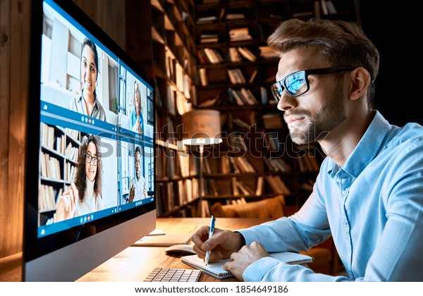 Business man having virtual team meeting on video\
conference call using computer. Social distance employee working\
from home office talking to diverse colleagues in remote\
videoconference online\
chat.