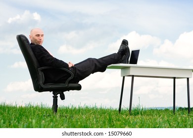 A business man with his feet up on a desk outside.