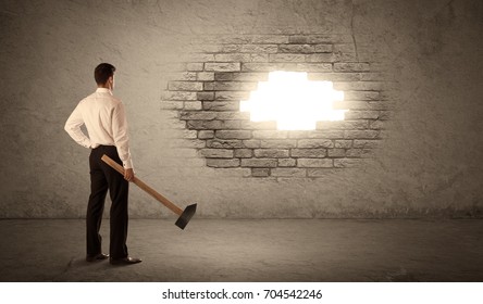 Business man hitting brick grungy wall with hammer and opening a hole