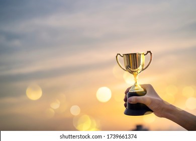 Business man hold a trophy showing success until receiving the award, city background. Champion golden trophy for winner background.