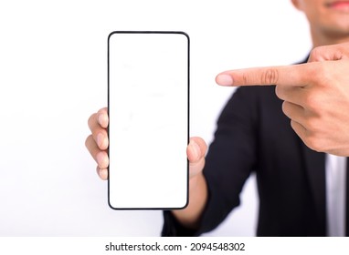 Business Man Holding Big Smartphone With White Blank Screen In Hand, Showing Close To Camera And Pointing At Device