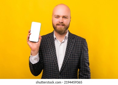 A Business Man Is Holding A Brand New Phone Over Yellow Wall .