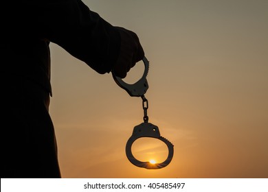Business Man holding handcuffs after releasing over sunset background. Freedom and Burden-free concept
