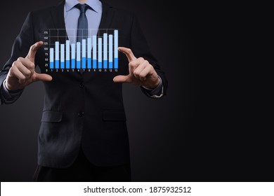 Business man holding holographic graphs and stock market statistics gain profits. Concept of growth planning and business strategy. Display of good economy form digital screen - Shutterstock ID 1875932512