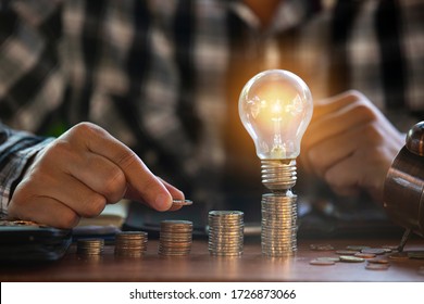 Geschäftsleute, die eine Glühbirne mit grünem Hintergrund halten, und die sie in einem Notizbuch für den Finanzsektor