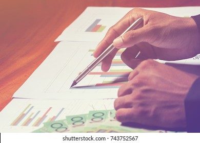 Business Man Holding Pen And Writing Note On The Wood Table,Checklist Note Financial Leverage Of Investment Data, Home Office Desk Background Textures Concept.