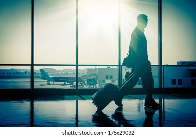 Business Man At International Airport Moving To Terminal Gate For Airplane Travel Trip - Mobility Concept And Aerospace Industry Flight Connections - Sunshine On Cold Blue Nostalgic Filtered Look