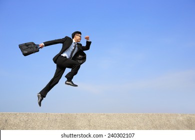 business man jump and run with blue sky background, full length, asian male - Powered by Shutterstock