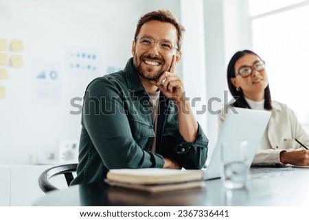 Business man listening to a discussion during a meeting in an office. Happy business man sitting in a boardroom with his colleagues.
