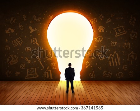 Business man looking at bright light bulb in the wall concept