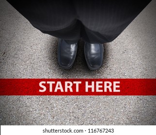 A Business Man Is Looking Down At His Feet With A Red Race Line That Says Start Here To Represent A Journey,