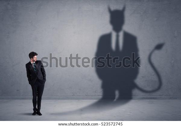 Business man looking at his own devil demon\
shadow concept\
background