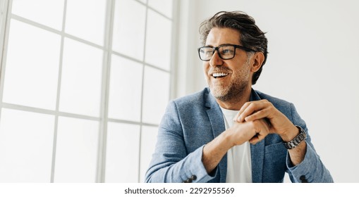 Business man looking outside the window in an office. Senior business man thinking about work while sitting at his desk in a suit. - Powered by Shutterstock