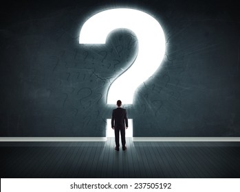 Business Man Looking At Wall With A Bright Question Mark Concept