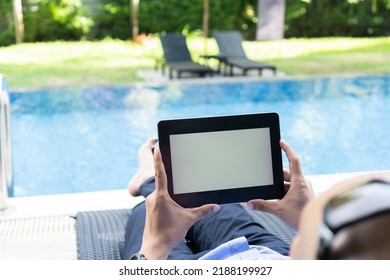 Business man lying on a chair at the swimming pool, holding a tablet with blank screen. - Powered by Shutterstock