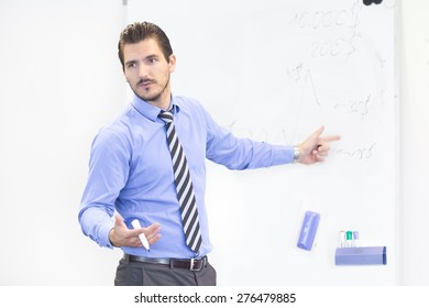 Business man making a presentation in front of whiteboard. Business executive delivering a presentation to his colleagues during meeting or in-house business training, explaining business plans.