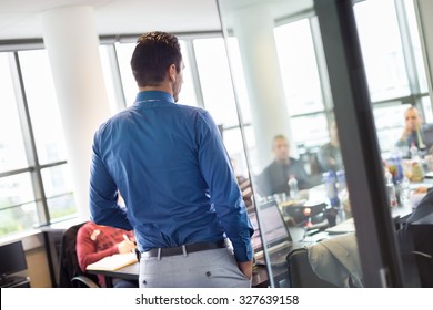 Business Man Making A Presentation At Office. Business Executive Delivering A Presentation To His Colleagues During Meeting Or In-house Business Training. View Through Glass.