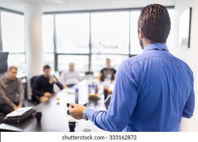 Business Man Making A Presentation At Office. Business Executive Delivering A Presentation To His Colleagues During Meeting Or In-house Business Training, Explaining Business Plans To His Employees. 